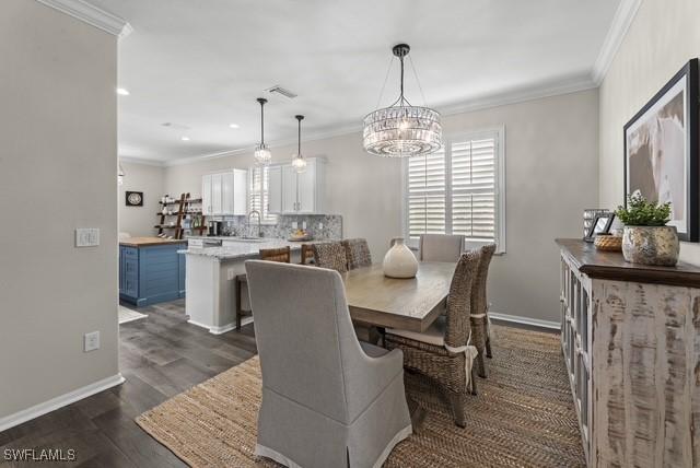 dining room with crown molding, dark hardwood / wood-style flooring, and sink