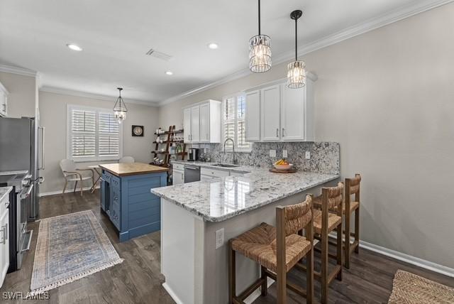 kitchen featuring appliances with stainless steel finishes, blue cabinets, a kitchen breakfast bar, and white cabinets