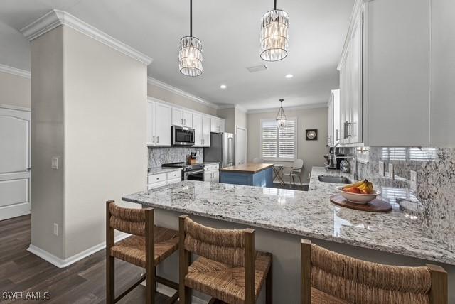 kitchen with sink, white cabinetry, a kitchen island, stainless steel appliances, and decorative backsplash