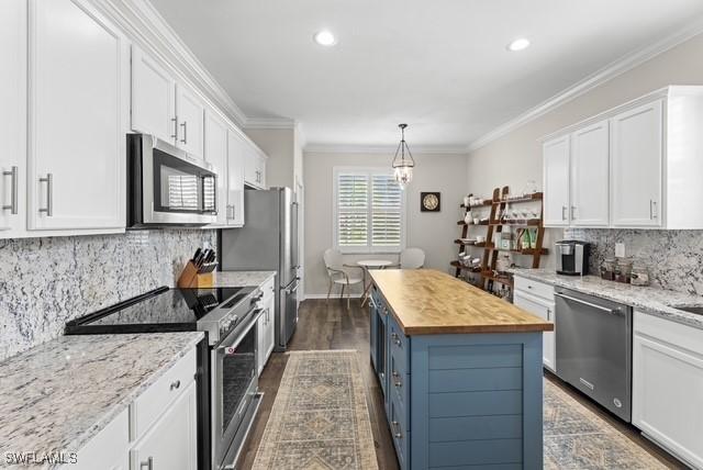 kitchen with white cabinets, a kitchen island, appliances with stainless steel finishes, and wooden counters