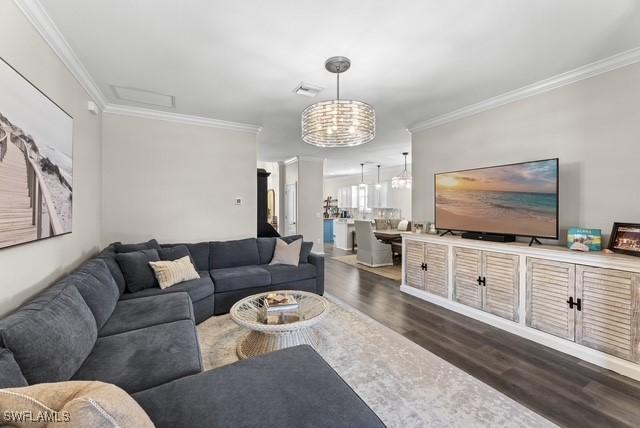 living room with crown molding and dark wood-type flooring