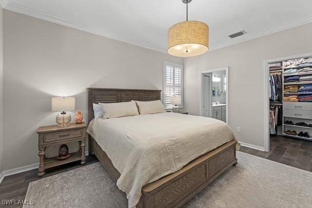 bedroom with crown molding, a walk in closet, dark hardwood / wood-style flooring, and a closet