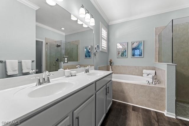 bathroom with crown molding, wood-type flooring, plus walk in shower, and vanity