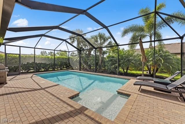 view of pool featuring grilling area, a patio area, and glass enclosure