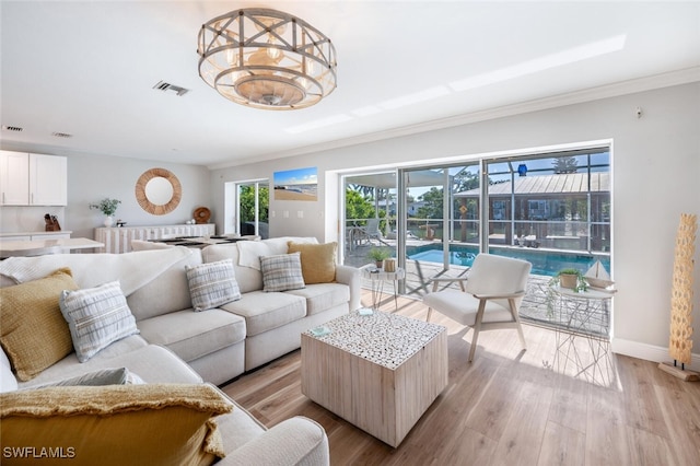 living area with visible vents, a healthy amount of sunlight, light wood-type flooring, and baseboards