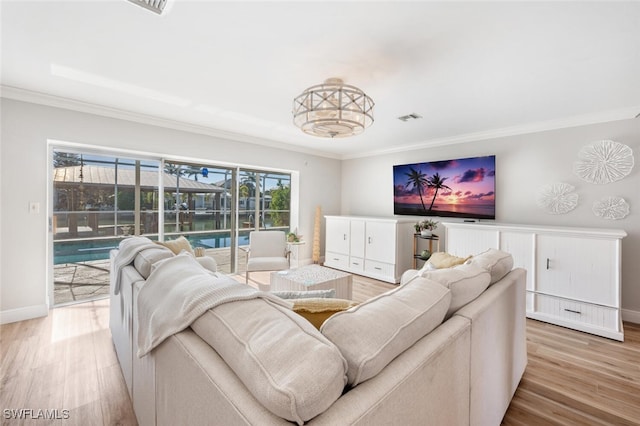 living room with crown molding, baseboards, visible vents, and light wood-type flooring