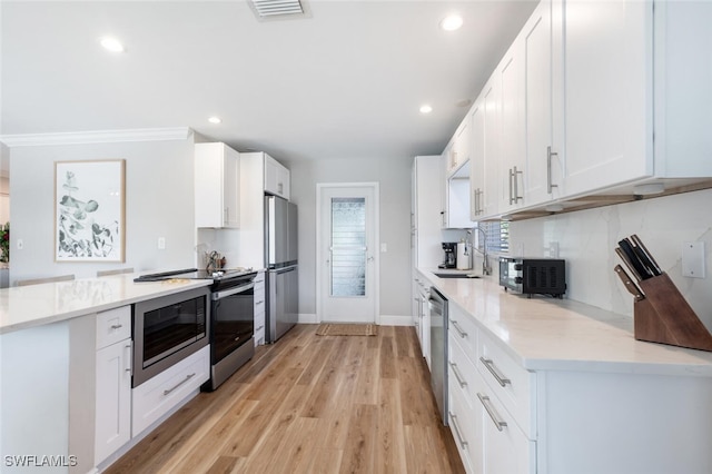 kitchen featuring visible vents, appliances with stainless steel finishes, white cabinetry, and a sink