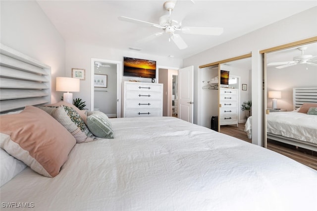 bedroom featuring visible vents, a ceiling fan, multiple closets, and wood finished floors