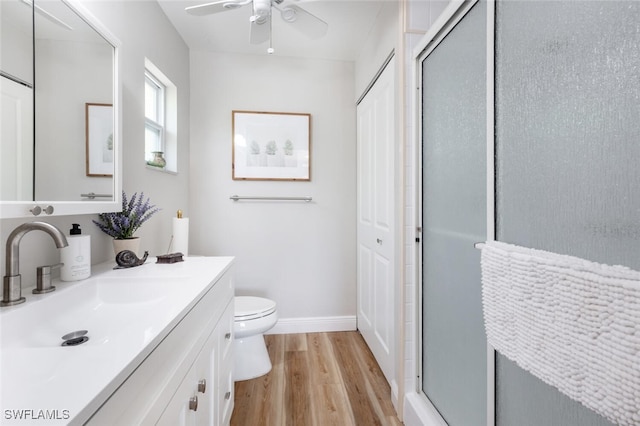 bathroom featuring a shower stall, ceiling fan, toilet, wood finished floors, and vanity