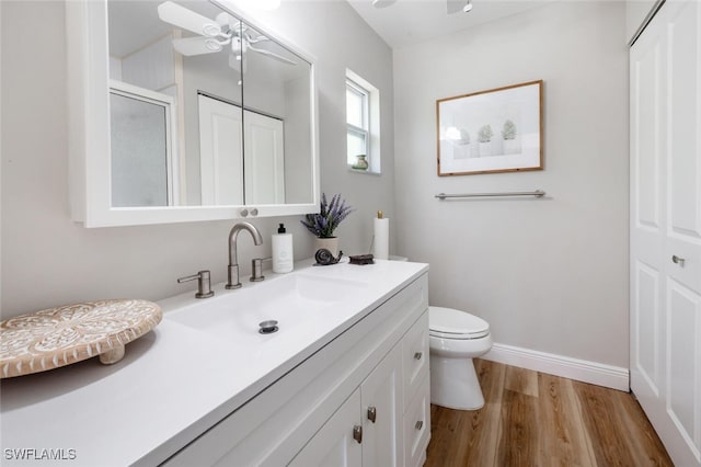 full bathroom featuring toilet, a ceiling fan, wood finished floors, baseboards, and vanity