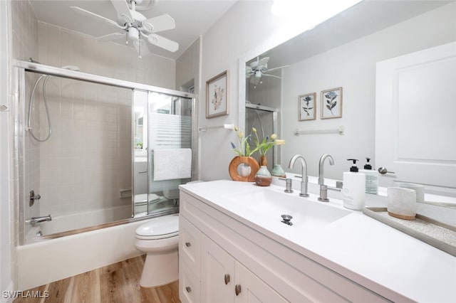 full bathroom with toilet, a ceiling fan, wood finished floors, enclosed tub / shower combo, and vanity