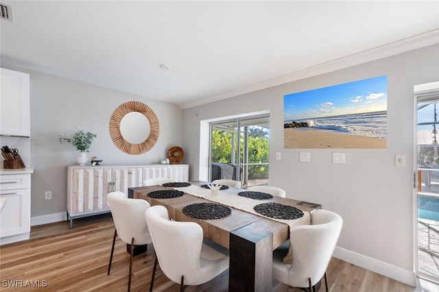 dining space with visible vents, light wood-style flooring, baseboards, and ornamental molding