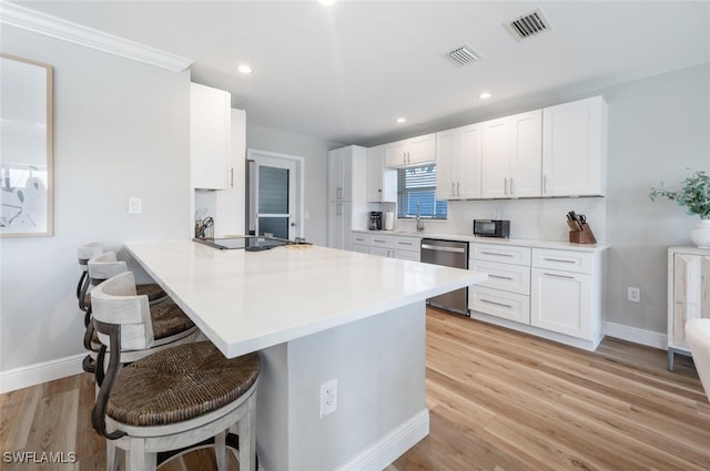 kitchen with stainless steel dishwasher, white cabinetry, visible vents, and a kitchen bar