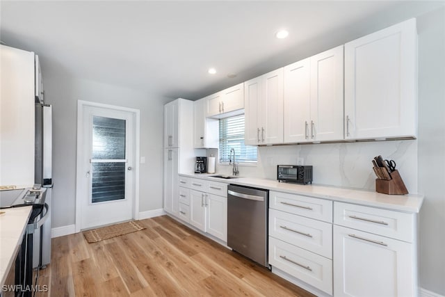 kitchen with a sink, light wood-style flooring, appliances with stainless steel finishes, and white cabinets