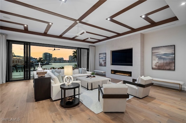 living room featuring coffered ceiling, a large fireplace, and light wood-type flooring