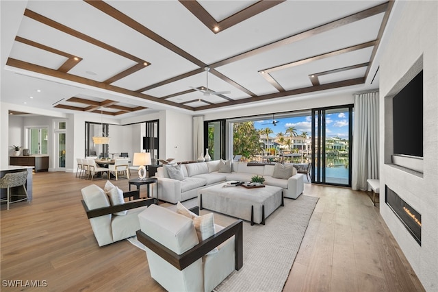 living room featuring coffered ceiling, light hardwood / wood-style flooring, beamed ceiling, ceiling fan, and a fireplace