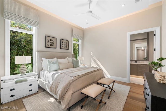 bedroom with ceiling fan, ensuite bath, and light hardwood / wood-style flooring