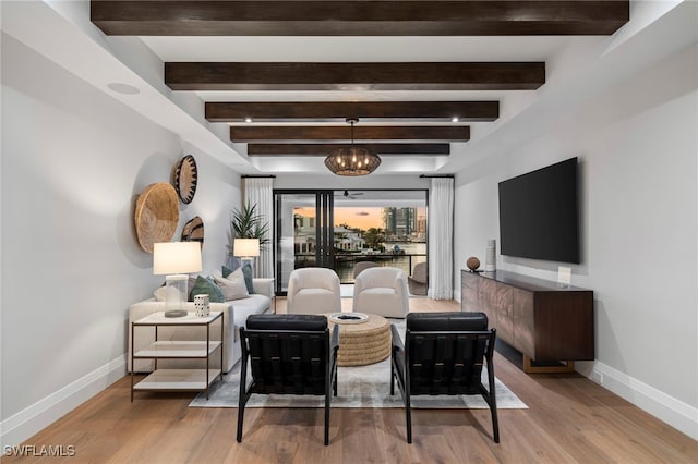 living room with beamed ceiling, light hardwood / wood-style floors, and a chandelier