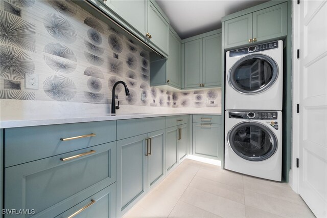 washroom featuring cabinets, stacked washing maching and dryer, sink, and light tile patterned flooring