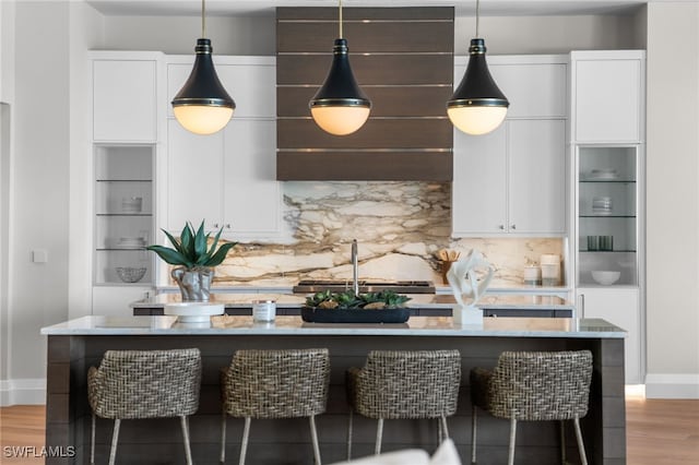 kitchen featuring tasteful backsplash, white cabinets, a kitchen breakfast bar, and light hardwood / wood-style floors