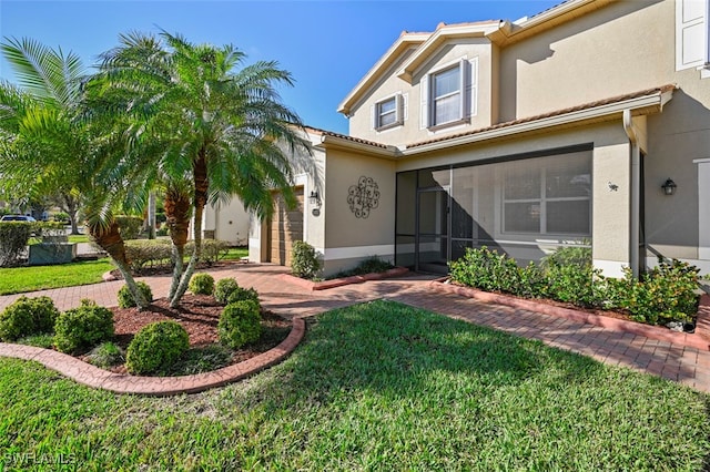 view of front of property featuring a front lawn, an attached garage, and stucco siding