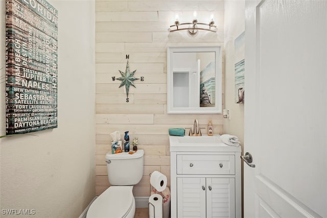 bathroom featuring vanity, toilet, and wood walls