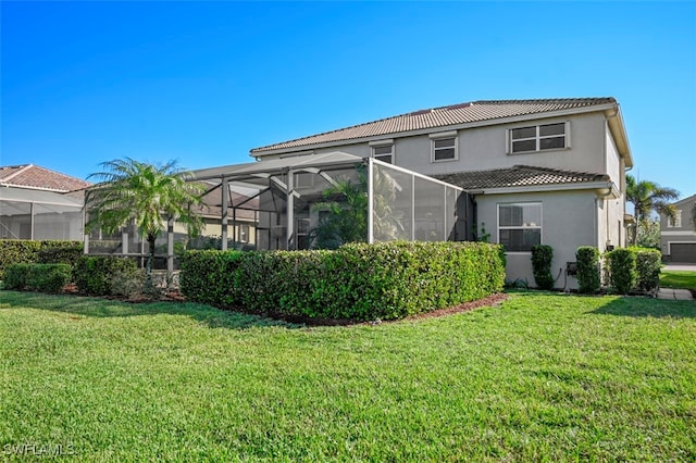 rear view of house with a yard and a lanai