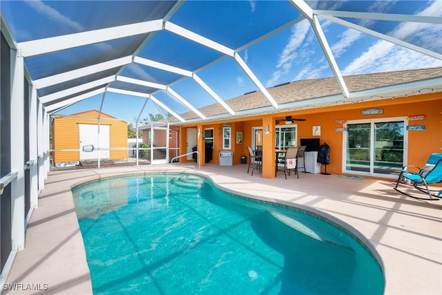 view of pool with ceiling fan, a storage unit, a patio area, and glass enclosure