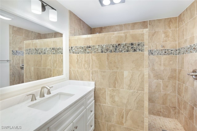 bathroom with tiled shower and vanity