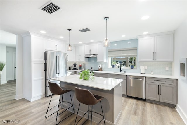 kitchen featuring sink, appliances with stainless steel finishes, white cabinetry, and a center island