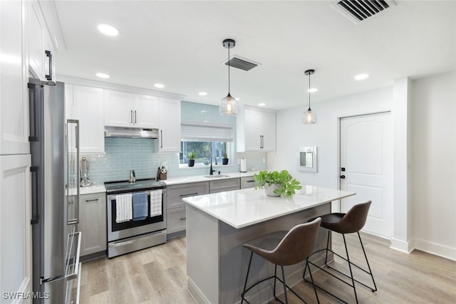 kitchen featuring stainless steel appliances, hanging light fixtures, a center island, light hardwood / wood-style floors, and white cabinets