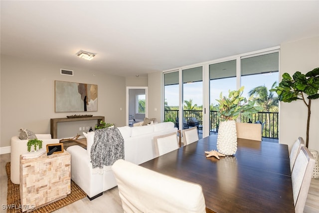 dining space with expansive windows and light hardwood / wood-style flooring