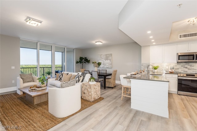 living room with expansive windows, sink, and light hardwood / wood-style flooring