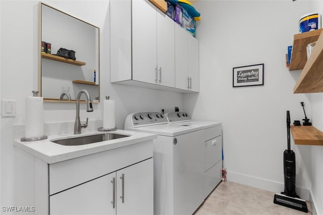 clothes washing area with sink, washer and clothes dryer, and cabinets