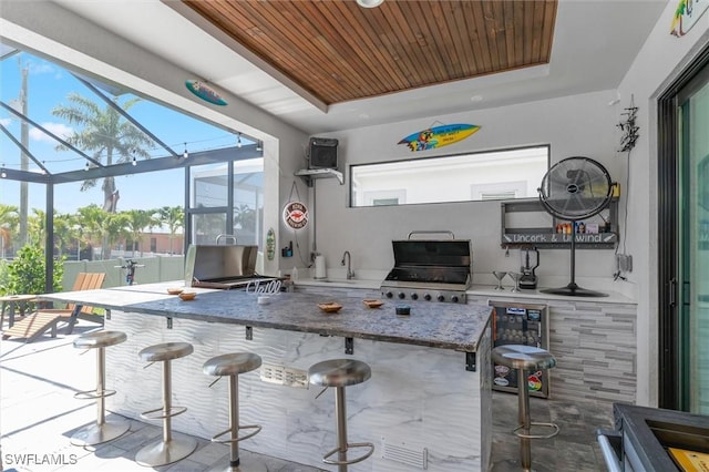 kitchen featuring a breakfast bar, sink, wooden ceiling, a tray ceiling, and beverage cooler