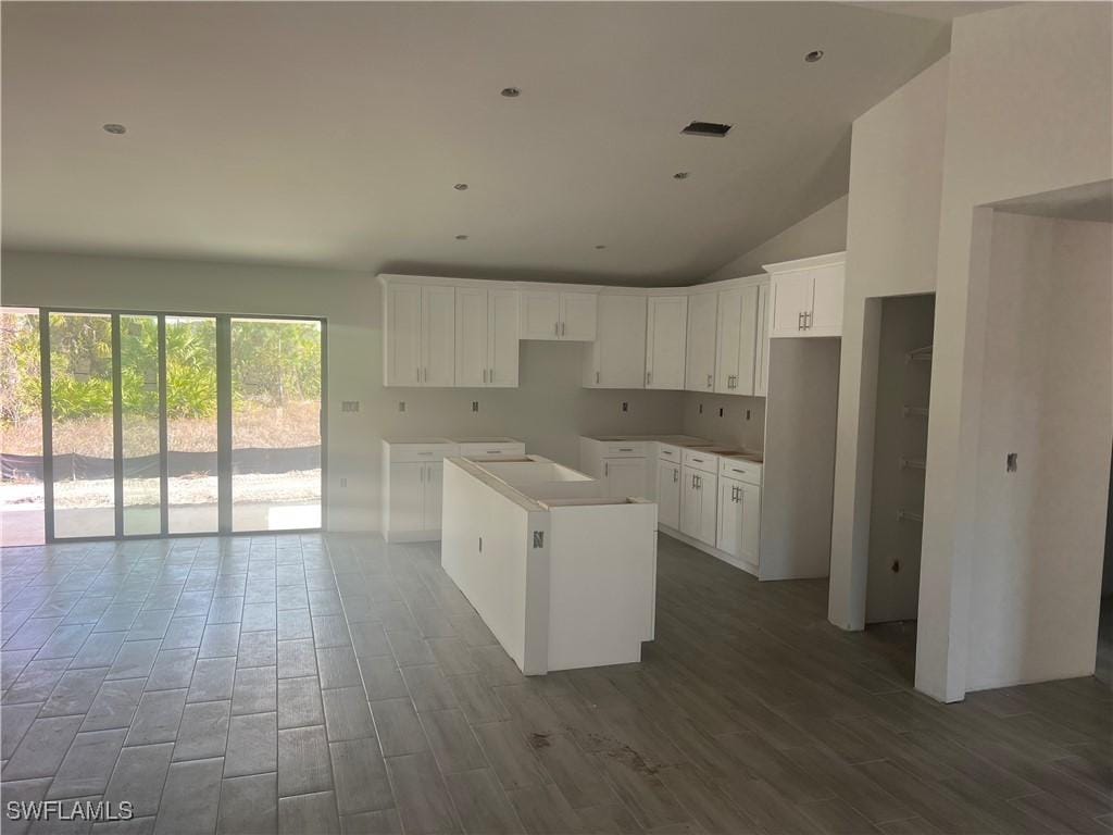 kitchen featuring white cabinetry, vaulted ceiling, a center island, and hardwood / wood-style floors