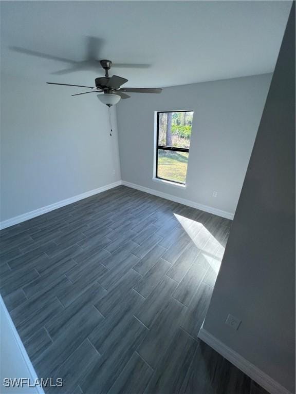 unfurnished room featuring ceiling fan, baseboards, and dark wood-style flooring