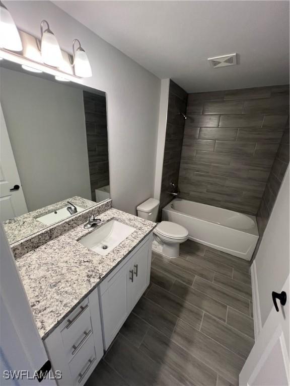 full bathroom with visible vents, toilet, bathtub / shower combination, and vanity