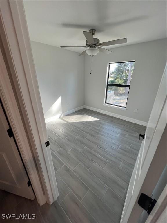 empty room featuring wood finish floors, a ceiling fan, and baseboards