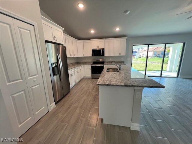 kitchen featuring wood tiled floor, recessed lighting, a sink, white cabinets, and appliances with stainless steel finishes