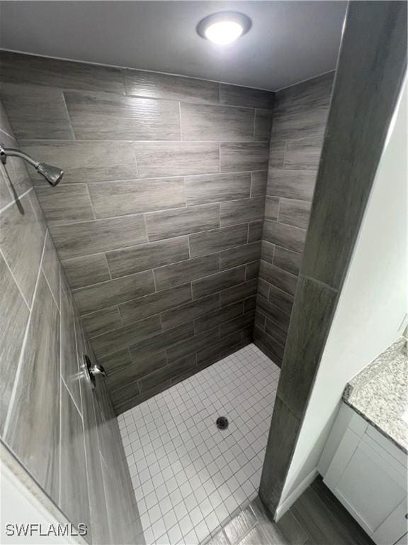 bathroom with tiled shower and vanity