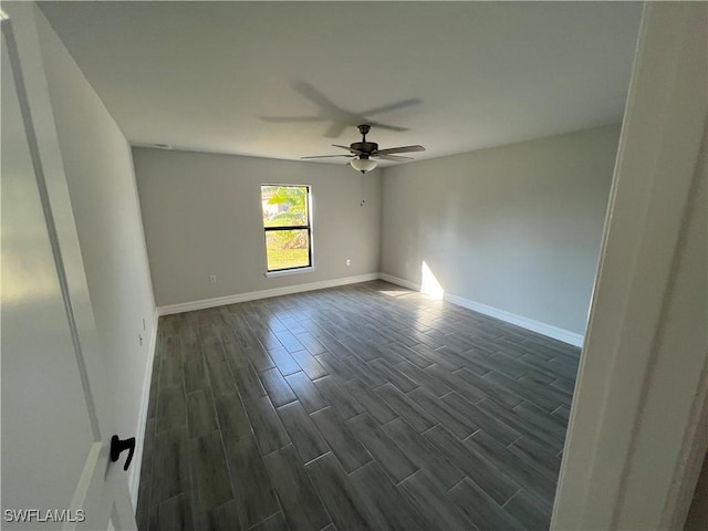 unfurnished room featuring baseboards, dark wood-style flooring, and ceiling fan