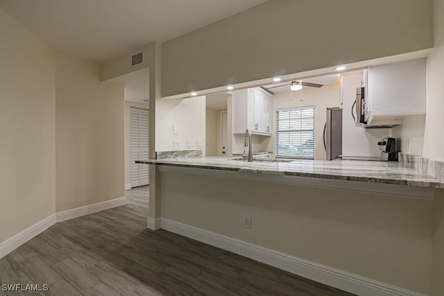 kitchen featuring sink, appliances with stainless steel finishes, light stone counters, white cabinets, and kitchen peninsula