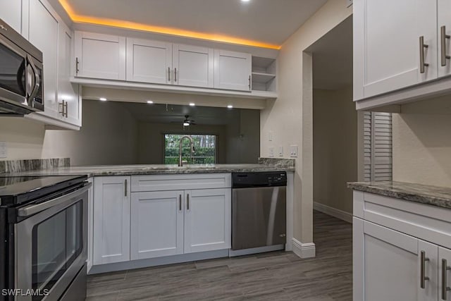 kitchen with dark stone counters, appliances with stainless steel finishes, dark wood-style flooring, open shelves, and a sink