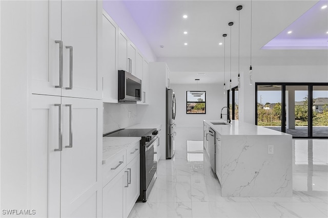 kitchen featuring sink, white cabinetry, decorative light fixtures, an island with sink, and stainless steel appliances