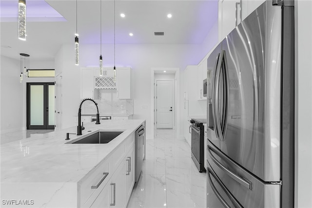 kitchen with sink, light stone counters, decorative light fixtures, appliances with stainless steel finishes, and white cabinets