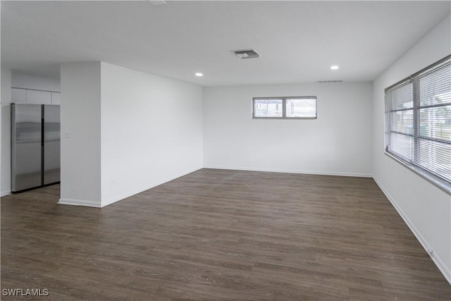 empty room with dark hardwood / wood-style flooring and a wealth of natural light