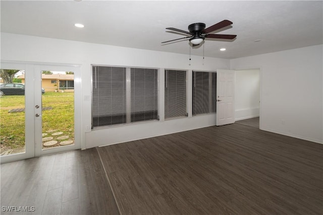 empty room with a healthy amount of sunlight, dark wood-type flooring, ceiling fan, and french doors