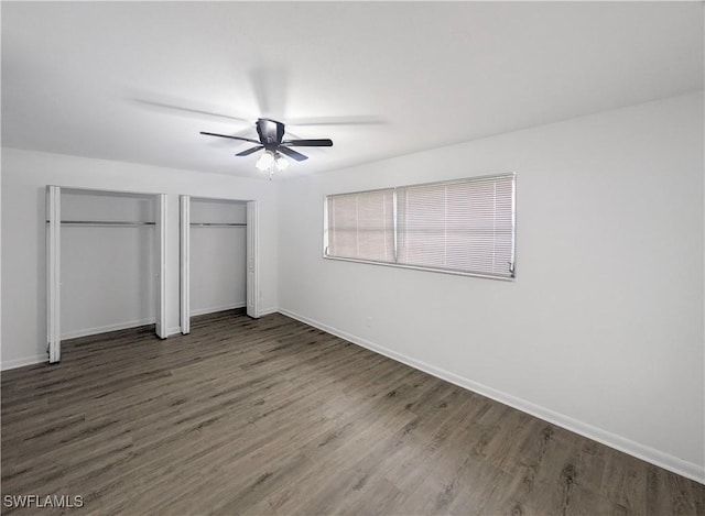 unfurnished bedroom with multiple closets, ceiling fan, and dark hardwood / wood-style floors