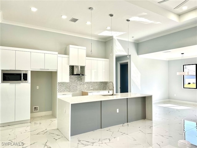 kitchen featuring sink, white cabinets, hanging light fixtures, a center island with sink, and wall chimney exhaust hood